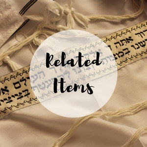May include: A white tallit prayer shawl featuring a gold-colored atarah band embroidered with black Hebrew text. The garment includes white tzitzit fringes at the corners and a semi-transparent circular overlay with the text Related Items.