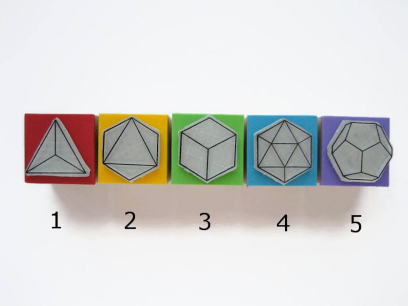 May include: Five wooden blocks, each with a different geometric shape outlined in black. The blocks are arranged in a row from left to right, with the colors red, yellow, green, blue, and purple. The shapes are a triangle, a circle, a cube, a hexagon, and an octagon. The numbers 1 through 5 are printed below the blocks.