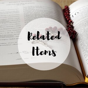 May include: A close-up of an open book with a rosary draped over it. The book is open to a page with text in Polish. The rosary is made of red beads and has a silver crucifix. The text "Related Items" is written in a circle over the image.