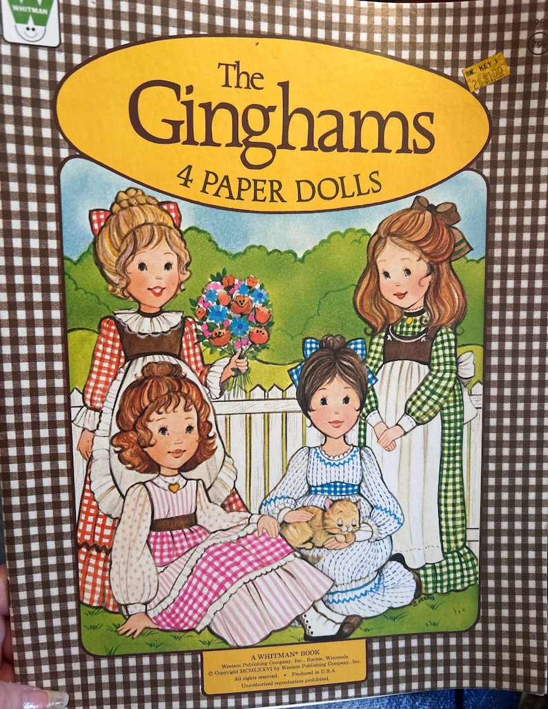 May include: A vintage Whitman paper doll book featuring four girls in gingham dresses. The book cover has a yellow title bar with the text "The Ginghams 4 Paper Dolls".