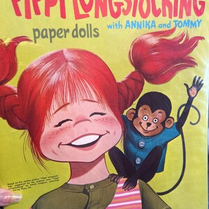 May include: A vintage paper doll book featuring Pippi Longstocking with Annika and Tommy. The cover features a colorful illustration of Pippi with her signature red hair and a monkey on her shoulder.