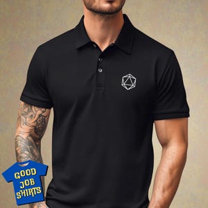 May include: Black polo shirt with a white geometric design on the left chest. The design resembles a 20-sided die.