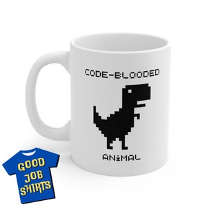 May include: White ceramic mug with a black and white pixelated dinosaur graphic and the text "CODE-BLOODED ANIMAL".