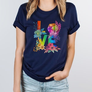 May include: A navy blue t-shirt with a rainbow "LOVE" graphic featuring a 20-sided die and floral accents.