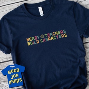 May include: A navy blue t-shirt with the text "Nerdy Teachers Build Characters" in rainbow colours. A dice symbol is between the words "Nerdy" and "Teachers".
