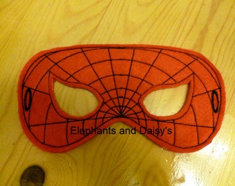 Puede incluir: Máscara de Spider-Man de fieltro rojo con telaraña negra y agujeros para los ojos. La máscara tiene un borde de fieltro negro y el texto "Elephants and Daisy's" está impreso en la parte inferior.