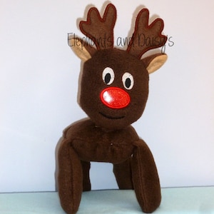 May include: Brown plush reindeer toy with a red nose and black eyes. The reindeer has brown antlers with a tan trim.