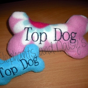 May include: Two plush dog bone toys, one pink with white and blue floral print and the other blue. Both toys have the text "Top Dog" embroidered on them.