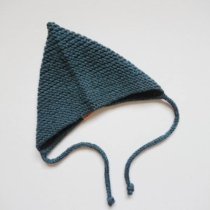 K&ouml;nnte beinhalten: Eine t&uuml;rkisfarbene, gestrickte Dreiecksm&uuml;tze mit langem Band. Die M&uuml;tze hat ein schlichtes Design und ist aus weichem, strukturiertem Garn gefertigt.