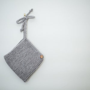 K&ouml;nnte beinhalten: Eine graue gestrickte Babyhaube mit einem Holzknopf und einer Schleife oben.