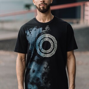 May include: A black t-shirt with a blue and white tie-dye effect and a circular graphic design featuring a repeating pattern of stylized letters.