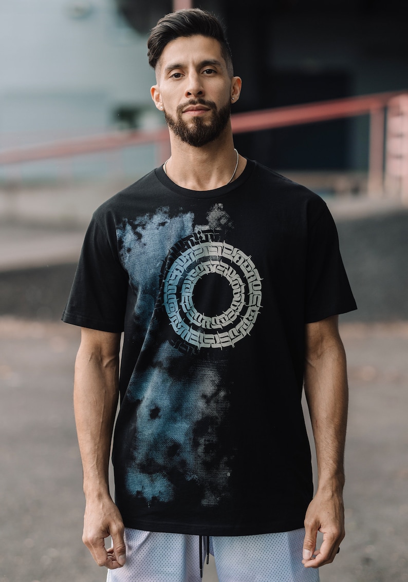 May include: A black t-shirt with a blue and white tie-dye effect and a circular graphic design featuring a repeating pattern of stylized letters.