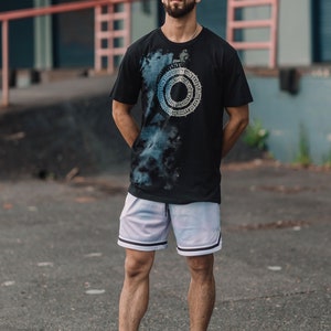 May include: A person wearing a black t-shirt with a blue and white circular design, white basketball shorts, and white sneakers.