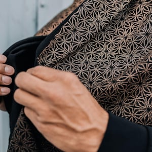 Peut inclure: Un v&ecirc;tement noir orn&eacute; d'un motif g&eacute;om&eacute;trique r&eacute;p&eacute;titif en forme d'&eacute;toiles dans une teinte cuivre ou bronze m&eacute;tallique. Le tissu pr&eacute;sente un design dense et complexe de lignes entrelac&eacute;es formant des &eacute;toiles sur toute la surface.
