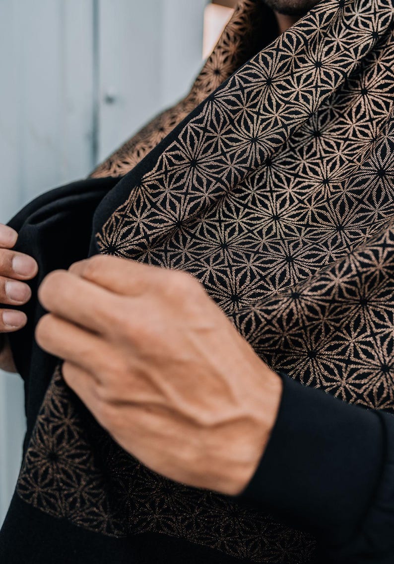 Peut inclure: Un v&ecirc;tement noir orn&eacute; d'un motif g&eacute;om&eacute;trique r&eacute;p&eacute;titif en forme d'&eacute;toiles dans une teinte cuivre ou bronze m&eacute;tallique. Le tissu pr&eacute;sente un design dense et complexe de lignes entrelac&eacute;es formant des &eacute;toiles sur toute la surface.