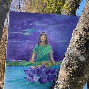 Könnte beinhalten: Quadratische Leinwandkunst mit einer ruhigen Szene. Eine Figur in einem grünen Oberteil meditiert über einer lila Lotusblume im Wasser. Der Hintergrund zeigt einen lila Himmel mit Andeutungen von Grün und Weiß. Das Kunstwerk wird im Freien ausgestellt, an einen Baum gelehnt.