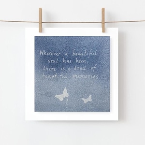 May include: A square print with a blue watercolour background, featuring the quote "Wherever a beautiful soul has been, there is a trail of beautiful memories." Two white butterfly illustrations are at the bottom. The print is hung with a wooden clip.
