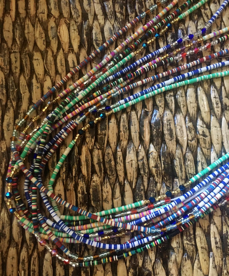 May include: A colorful beaded necklace with multiple strands of different colored beads. The beads are arranged in a striped pattern and are interspersed with small gold and silver beads.