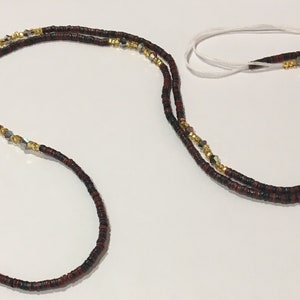 May include: A double-strand beaded necklace with black and red beads, gold beads, and silver beads. The necklace is tied with a white string.