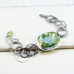 May include: A silver bracelet with a large green and white agate stone and a chain of hammered silver circles.