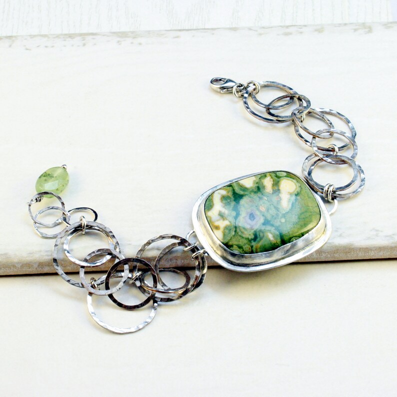 May include: A silver bracelet with a large green and white agate stone and a chain of hammered silver circles.