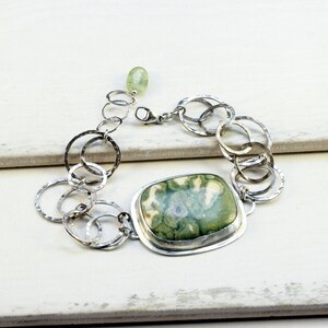 May include: A silver bracelet with a green and white agate stone and a hammered metal chain.