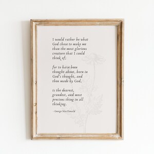 May include: A framed print with a white background and a black and white floral illustration. The print features a quote by George MacDonald: "I would rather be what God chose to make me than the most glorious creature that I could think of; for to have been thought about, born in God's thought, and then made by God, is the dearest, grandest, and most precious thing in all thinking."
