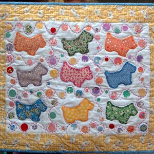 May include: A white quilt with a yellow border and a pattern of colorful dogs in circles. The dogs are made of fabric with different floral patterns.