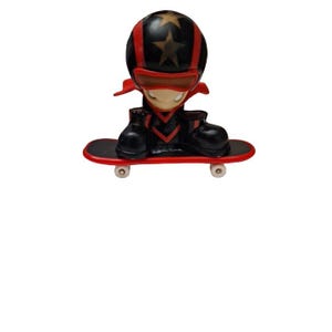 May include: A red and black fingerboard toy with a figure wearing a black helmet with a white star on it. The figure is riding a red skateboard with black wheels.