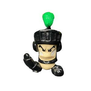 May include: A black and green fingerboard toy with a knight helmet and a menacing expression.