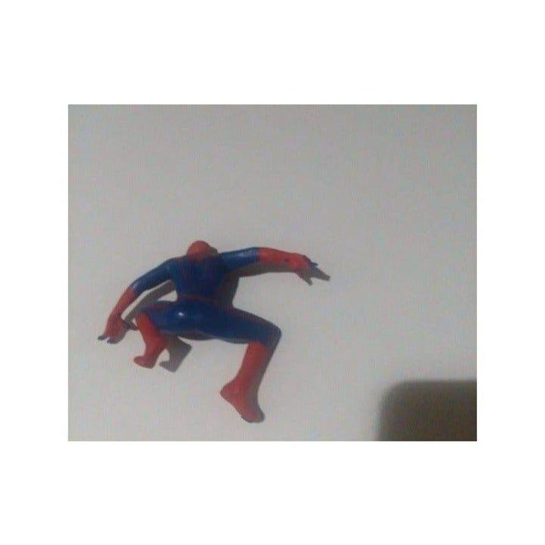 K&ouml;nnte beinhalten: Eine rote und blaue Plastik-Actionfigur von Spiderman in einer hockenden Pose mit ausgestreckten Armen.