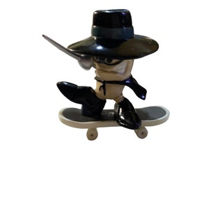 May include: A black and white fingerboard toy with a black hat and a silver sword. The figure is riding a white skateboard with black wheels.