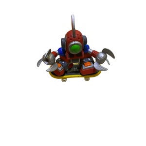 May include: A red, blue, and silver robot toy riding a yellow skateboard with the words "Tech Deck" printed on it.
