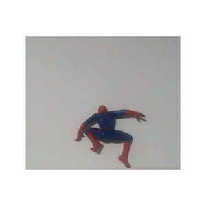 K&ouml;nnte beinhalten: Eine rote und blaue Plastik-Actionfigur von Spider-Man in einer hockenden Pose mit ausgestreckten Armen.