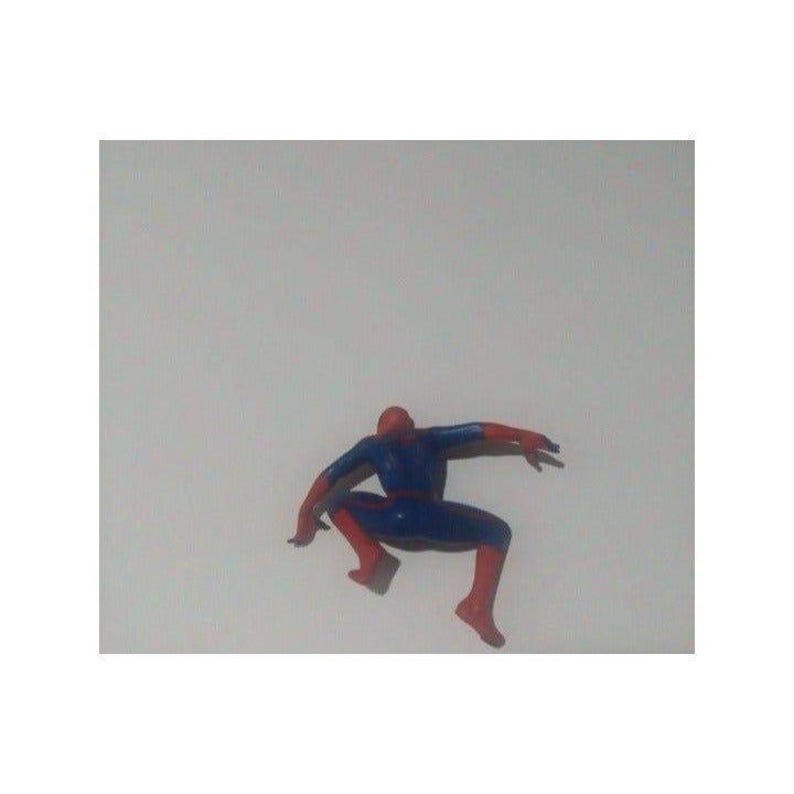 K&ouml;nnte beinhalten: Eine rote und blaue Plastik-Actionfigur von Spider-Man in einer hockenden Pose mit ausgestreckten Armen.