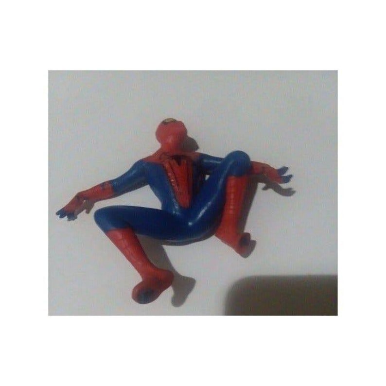 K&ouml;nnte beinhalten: Eine rote und blaue Plastik-Actionfigur von Spiderman in einer hockenden Pose. Die Figur tr&auml;gt einen roten und blauen Anzug mit einem Spinnenlogo auf der Brust.