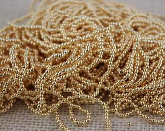 May include: A pile of small, gold-colored beads. The beads are round and have a smooth, shiny finish.