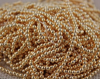 May include: A large pile of gold-colored round beads. The beads are small and have a shiny, metallic finish.