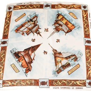 Puede incluir: Un pañuelo de seda blanco con un borde marrón que presenta un patrón repetido de círculos entrelazados. El centro del pañuelo presenta cuatro ilustraciones de iglesias de madera de Noruega, cada una con su nombre: "Urnes", "Hald Church", "Heddal" y "Eidsborg". El pañuelo está titulado "Stave Churches of Norway".