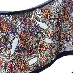 May include: A black velvet scarf with a gold and floral pattern. The scarf has a paisley design with red, purple, and gold flowers.
