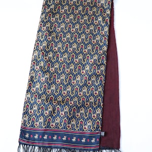 May include: A blue silk scarf with a gold and red pattern of horseshoes and horses. The scarf has a burgundy backing and black fringe.