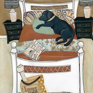 May include: A black Labrador Retriever dog is lying on a bed with a white frame and a brown patterned headboard. The dog is wearing a black collar with a silver buckle. There is a book on the bed with the text "SPRINKLERS FOR YOUR LAB BUY NOW TESTED FOR A HOT SUMMERS DAY! APPROVED". There is a brown and yellow bag with white polka dots and the text "I ADORE My Lab" on the floor next to the bed.