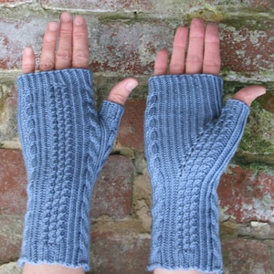 May include: A pair of blue fingerless gloves with a cable knit pattern. The gloves are made of a soft, warm yarn and are perfect for keeping your hands warm in the winter.