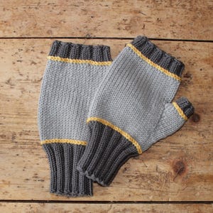 May include: Knitted fingerless gloves in grey with dark grey cuffs and a yellow stripe. The gloves are displayed on a wooden surface. These gloves are designed to keep hands warm while leaving fingers free.