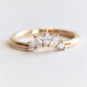 May include: A delicate gold band ring with a row of marquise and round diamonds set in a curved shape.