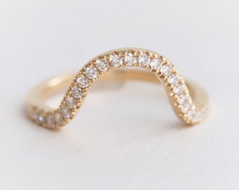 May include: A delicate gold ring with a wavy band set with small diamonds.