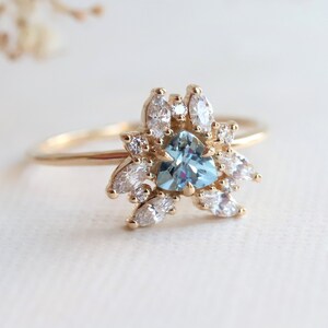 May include: A gold ring with a heart-shaped blue gemstone surrounded by smaller white gemstones.