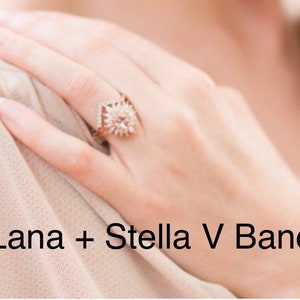 May include: A rose gold ring with a central, round, light-colored gemstone, surrounded by smaller stones in a starburst design. The ring is on a hand, with the text "Lana + Stella V Band" in the image.