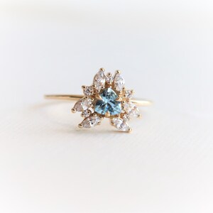 May include: A gold ring with a blue heart-shaped gemstone surrounded by smaller white gemstones.