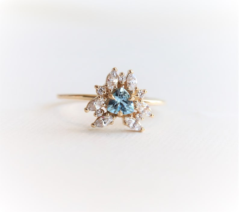 May include: A gold ring with a blue heart-shaped gemstone surrounded by smaller white gemstones.